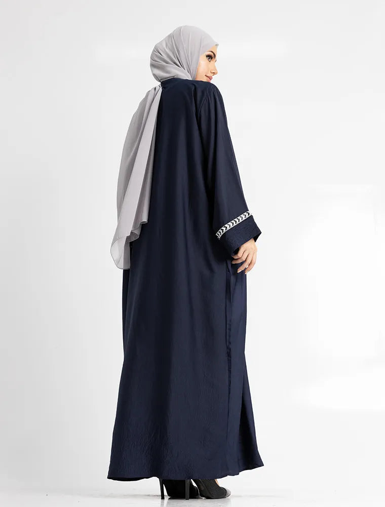 Woman wearing a navy abaya with white hijab on a white background