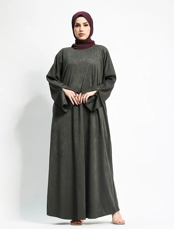 A woman modeling a dark gray long-sleeved abaya dress with a matching deep plum hijab, standing against a plain white studio background.