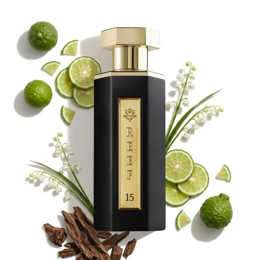 Perfume bottle labeled 'REEF 15' surrounded by limes, leaves, and flowers on a white background