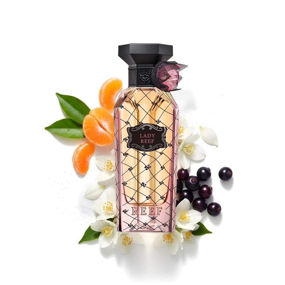 Perfume bottle labeled 'Lady Reef' surrounded by flowers and fruits on a white background