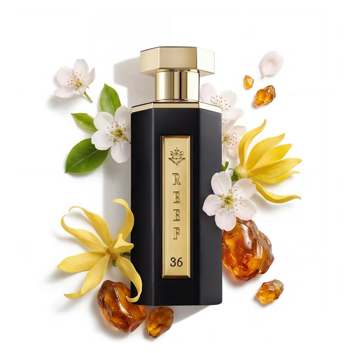 Perfume bottle with gold cap and black body surrounded by flowers and amber elements on a white background