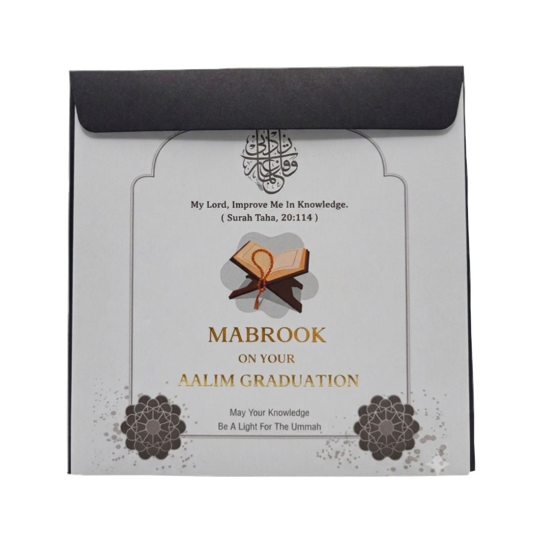 A square graduation card or booklet with a black envelope-style flap at the top, printed with Islamic text, an open book illustration, and decorative floral motifs on a light background.
