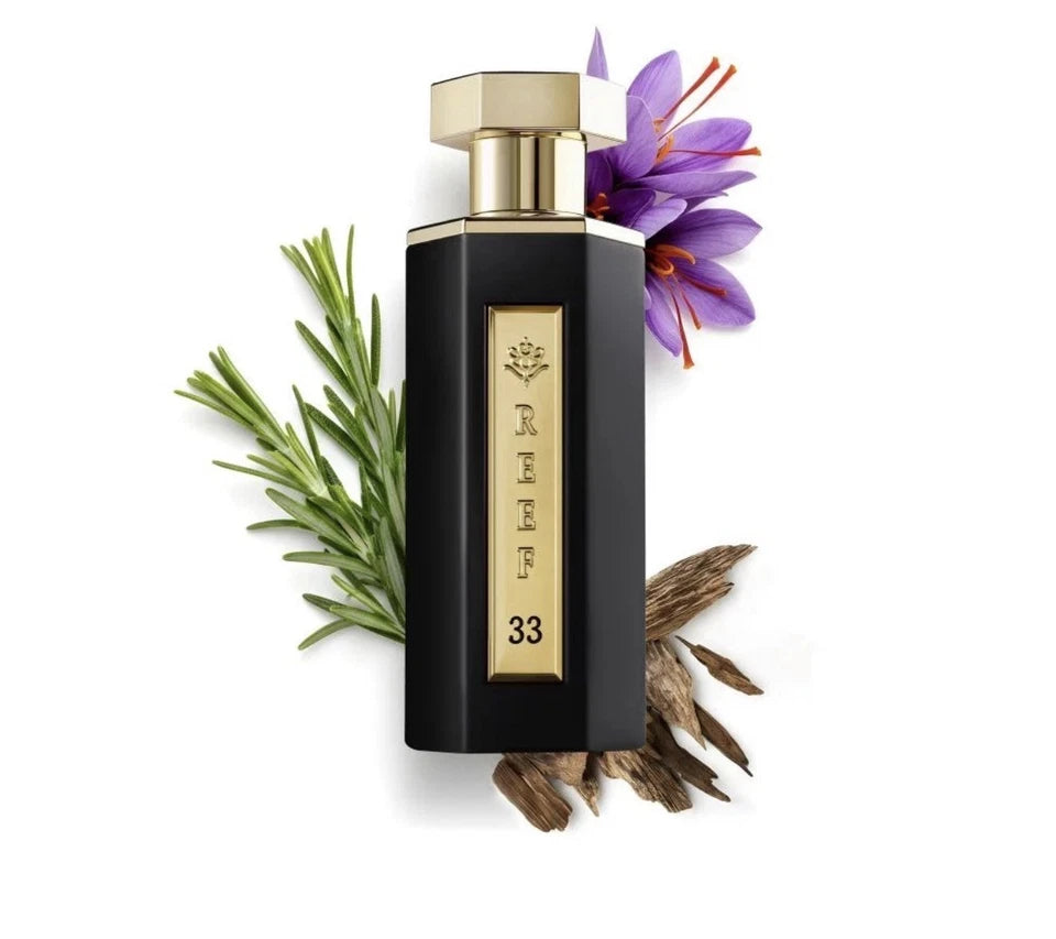 A black rectangular perfume bottle with a gold cap and a vertical gold label reading 'RIFAE 33', styled with green rosemary sprigs, dried herbs, and a purple flower on a white background.